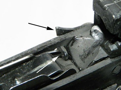 When the magazine runs empty, the follower presses up on a small tab (white arrow) and causes an internal last shot hold-open (black arrow) to lock the slide in the open position.