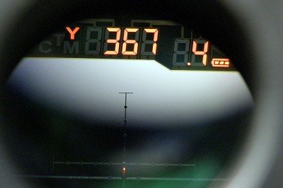 With the scope turned on (by pushing the on/range button on either side) simply push the range button to get a target solution. The “Y” on the left means the computer is set to yards instead of its alternate setting of meters. The middle number is the distance to the target, and the number to the right is the number of dots to hold into the wind per every 10 mph of crosswind. To the far right, the battery indicator is showing a full charge.