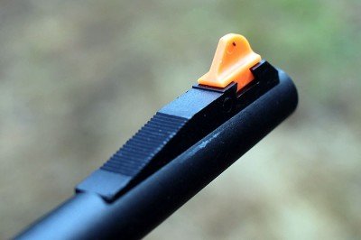 The front sight is wide, and orange (which makes it easy to see on the dark backdrop of the woods).