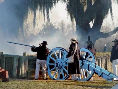 Reenactors loading a cannon on the actual site of the Battle of New Orleans.  They are dressed in the uniform of the US Navy. 