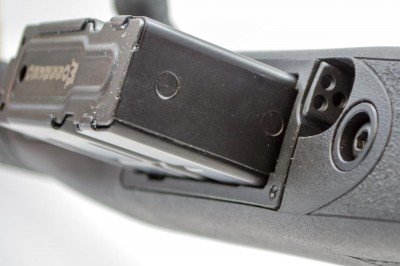 The magazine release lever is inset just forward of the magazine well.