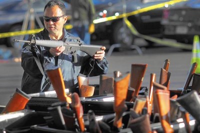 A man looks at a weapon at a gun buyback event at the Los Angeles Memorial Sports Arena in December 2012. Police officials say buybacks help drive down gun-related violence, but some experts question how effective these programs are. (Rick Loomis / Los Angeles Times)