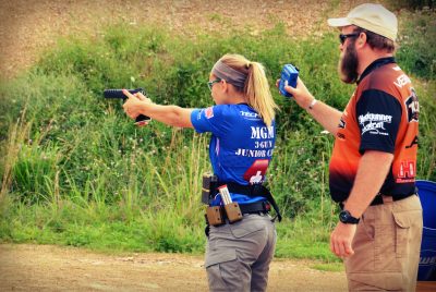 Dean DeTurk, instructing at the MGM Junior camp while Katie Francis shoots pistol.