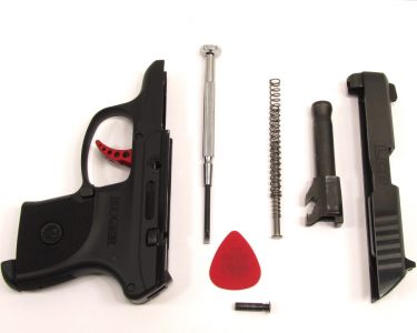 A small screwdriver is needed to pry the takedown pin from the frame for field stripping. The author uses a guitar pick to shield the slide from possible scratches.