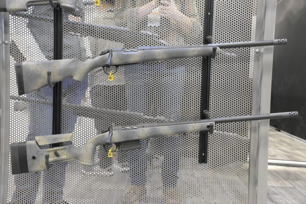 two rifles hanging on a metal panel.