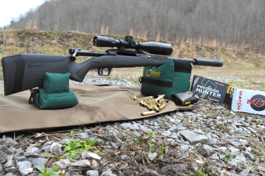 A suppressed rifle on shooting bags.