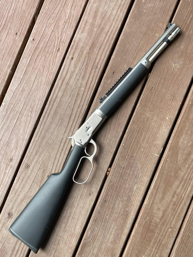 Taylor and Company Alaskan lever action rifle laid on vintage wood