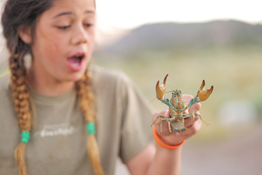 Girl outside holding a live crawdad