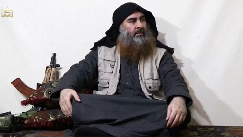 abu bakr al-baghdadi sitting with a rifle next to him