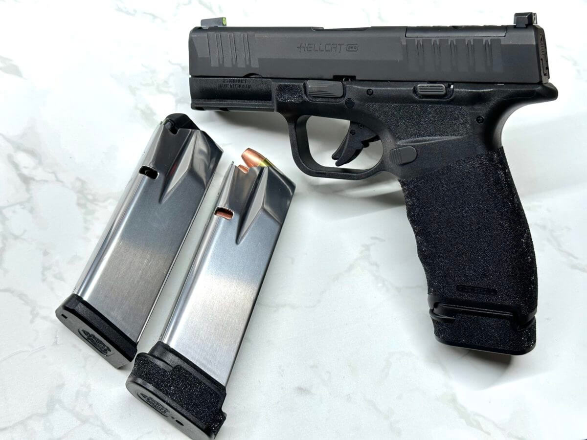 Two silver magazines lay next to a propped up black handgun.