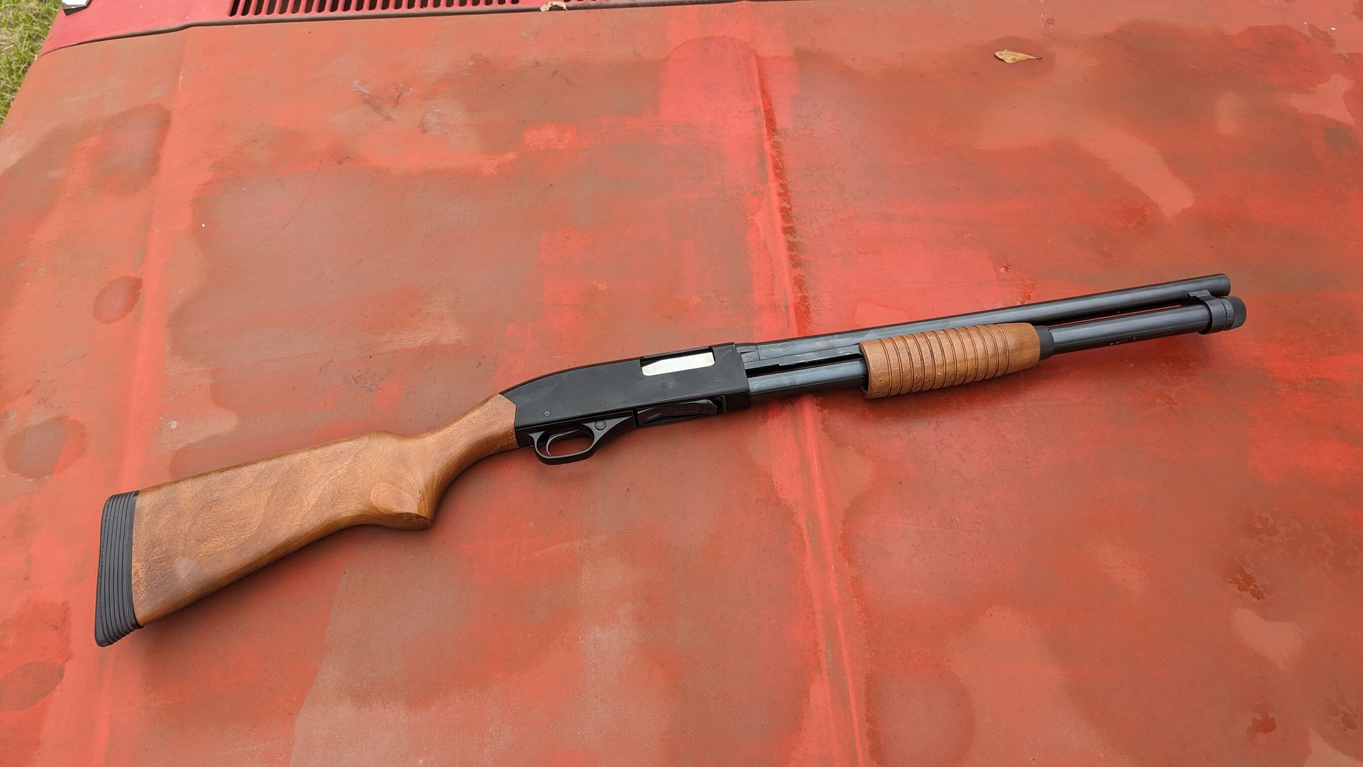 Winchester 1300 Defender series shotgun against orange vintage-style backdrop