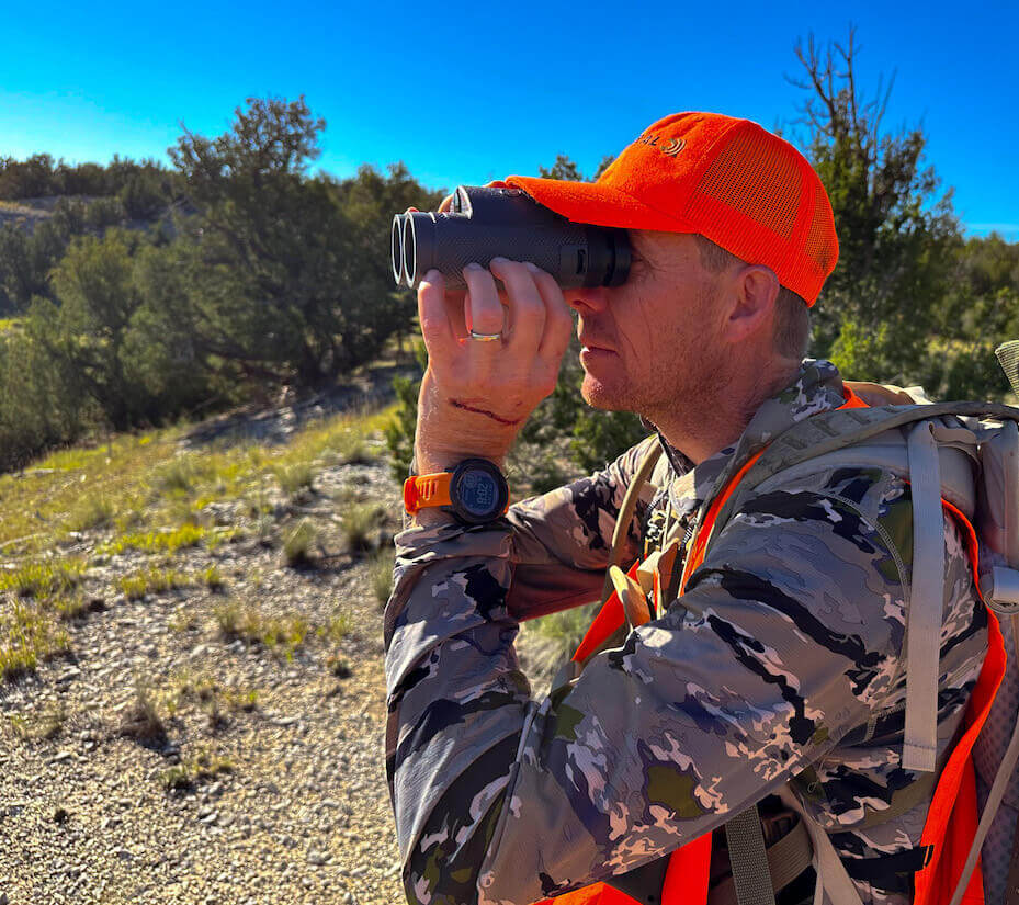 Hunter in camo and orange, looking through binos 
