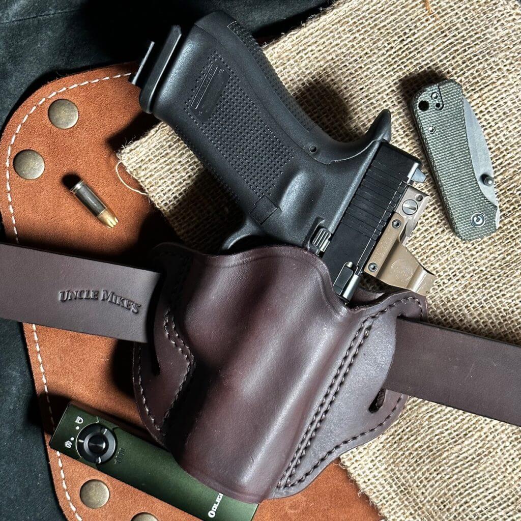 A leather holster and belt with a pistol.