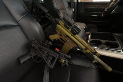 A SCAR and MP5 SBR sit in a truck seat.
