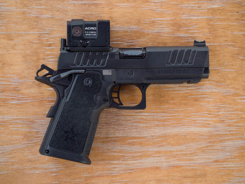 Full view of the right side of the weapon with the barrel pointing to the right. There is a red dot optic mounted at the rear of the slide and the hammer is cocked. The gun is black.