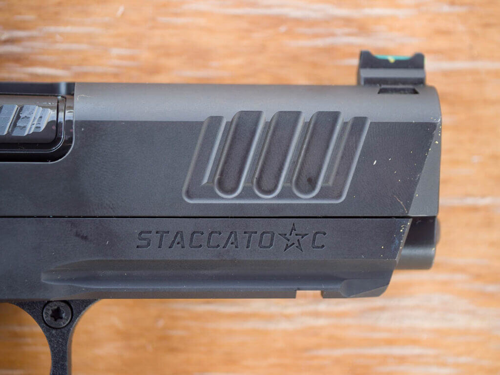 Close up view of the front of the right side of the gun with the slide closed, showing the front serrations and the fiber optic front sight.