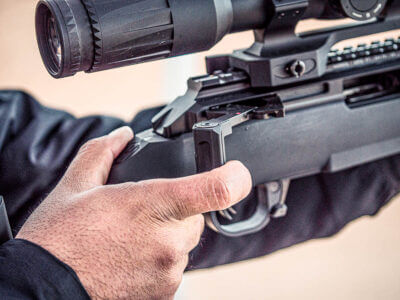 Close up photo of the action being worked with finger tips. The gun is pointing right.