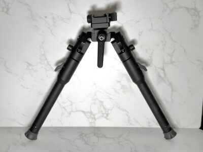 A bipod is staged against a white marble background.