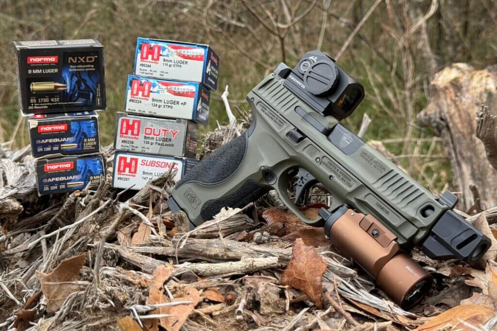 S&W Spec Series Metal M2.0 with boxes of ammo sitting in leaves and grass