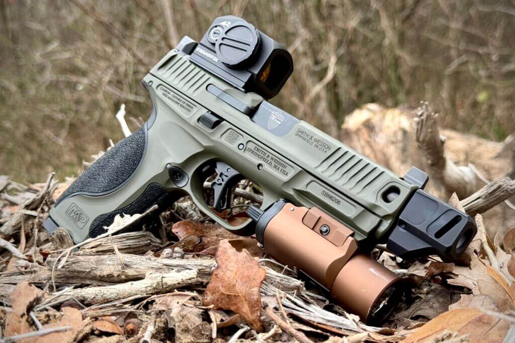 S&W Spec Series Metal M2.0 with handgun light resting on twigs and leaves outside