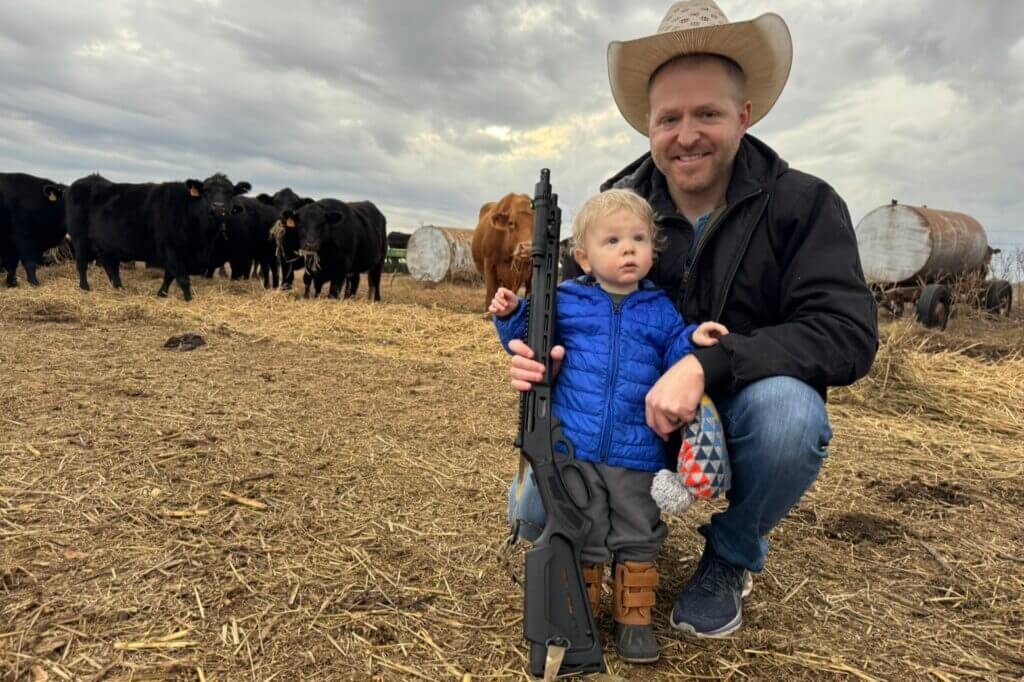 man and kid holding Marlin 1895 in a cow pasture