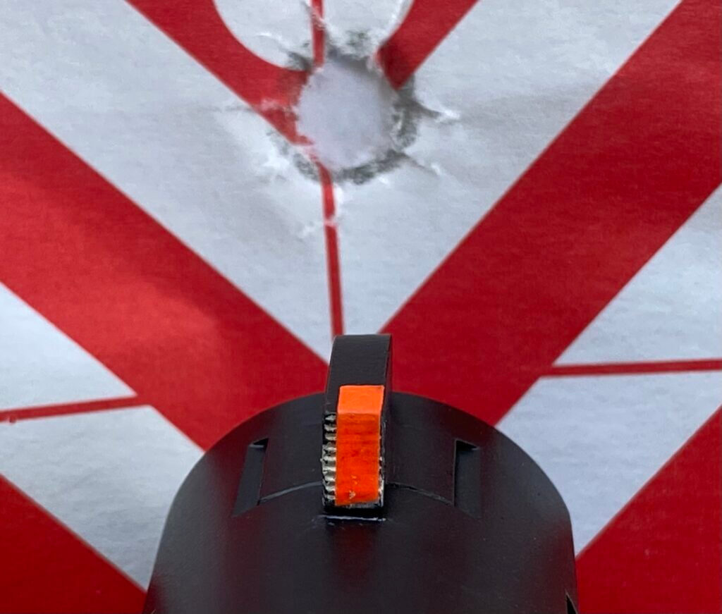 Orange tape on front sight aimed at hole in target