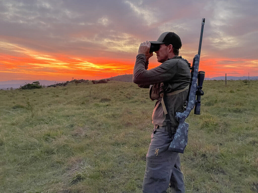 Man looking through spotting scope at sunset