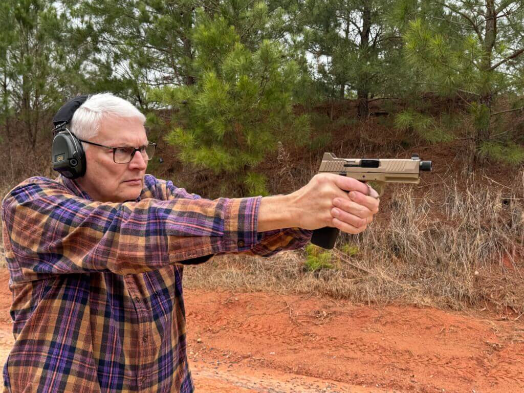 Man with hearing protection shooting the FN 545