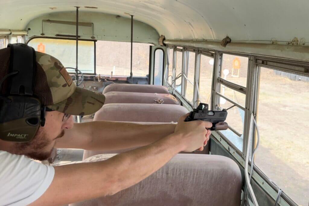 Aiming gun through window of old bus