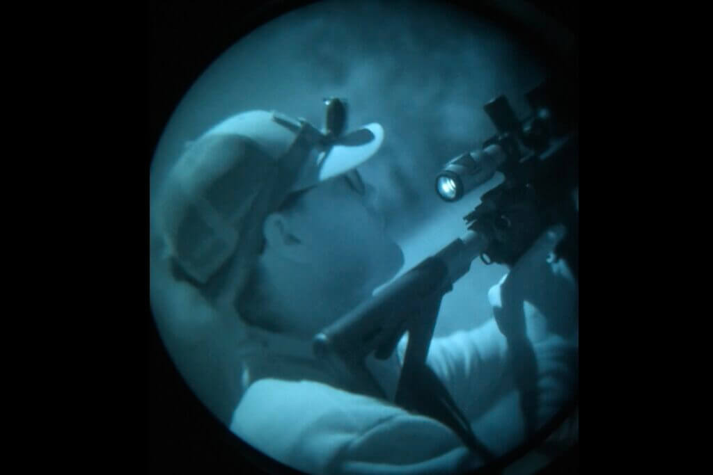 screen shot of hunter with rifle through night vision