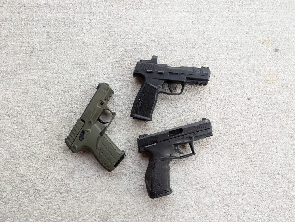 Three modern rimfire pistols on concrete