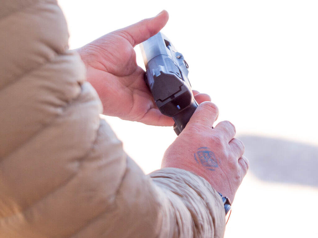 The gun is held in two hands but not in a shooting grip; the ready light shows it is not ready.