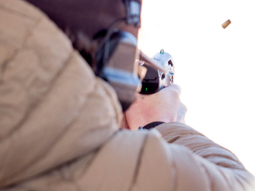 The gun si being shot away from the camera. The ready light and the front sight are lit green.