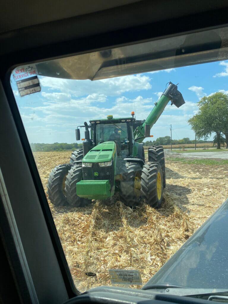 tractor and grain cart loading corn during harvest for private land access through farm work