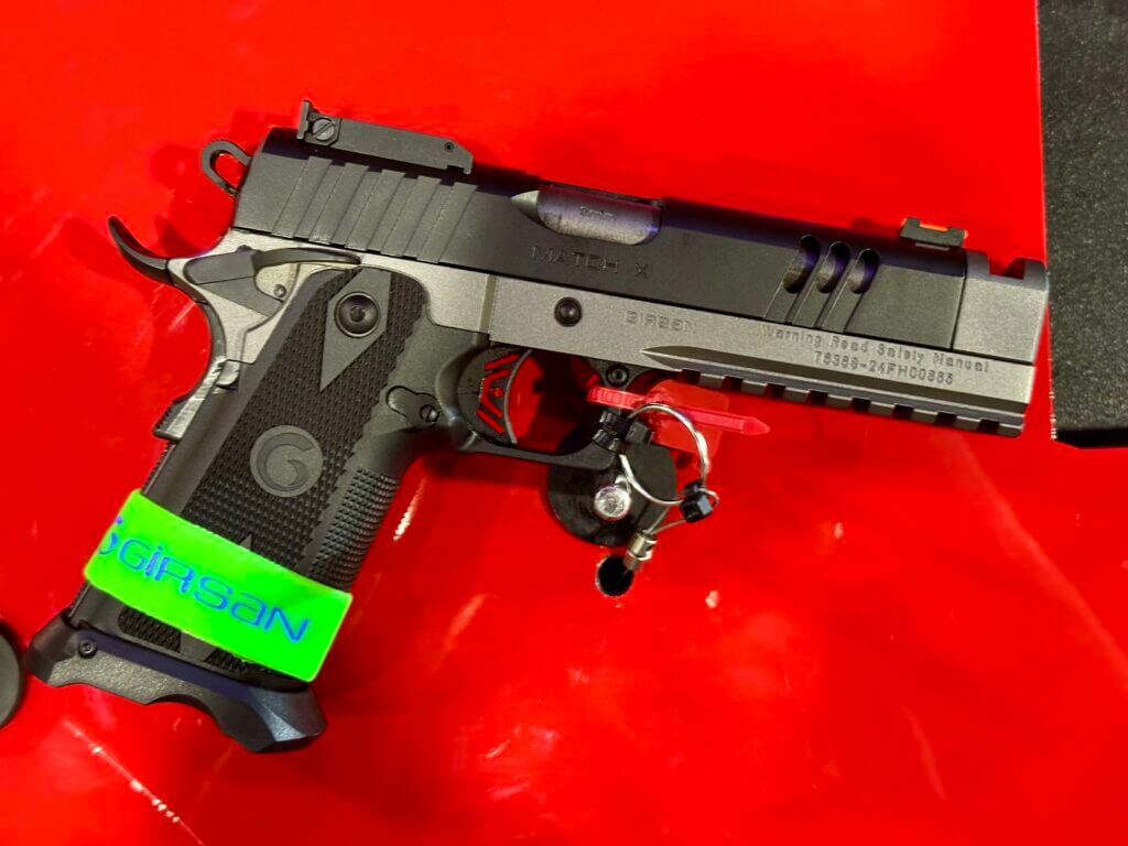 A black handgun lays on its side on a red table. It is pointed to the right.