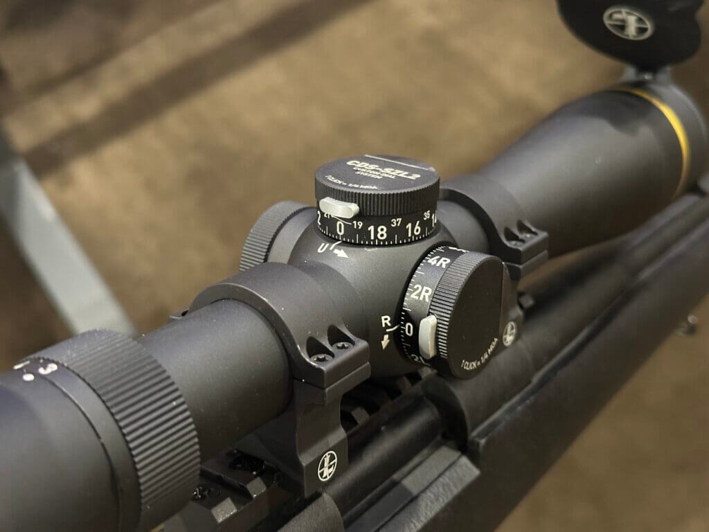 Closeup look at the elevation and windage turret of the rifle scope. The locking button for each is visible.