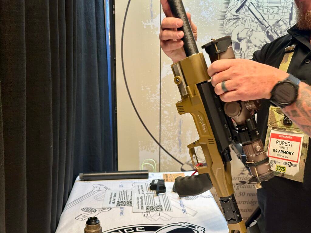 A man assembles the rifle by screwing the barrel into the action.