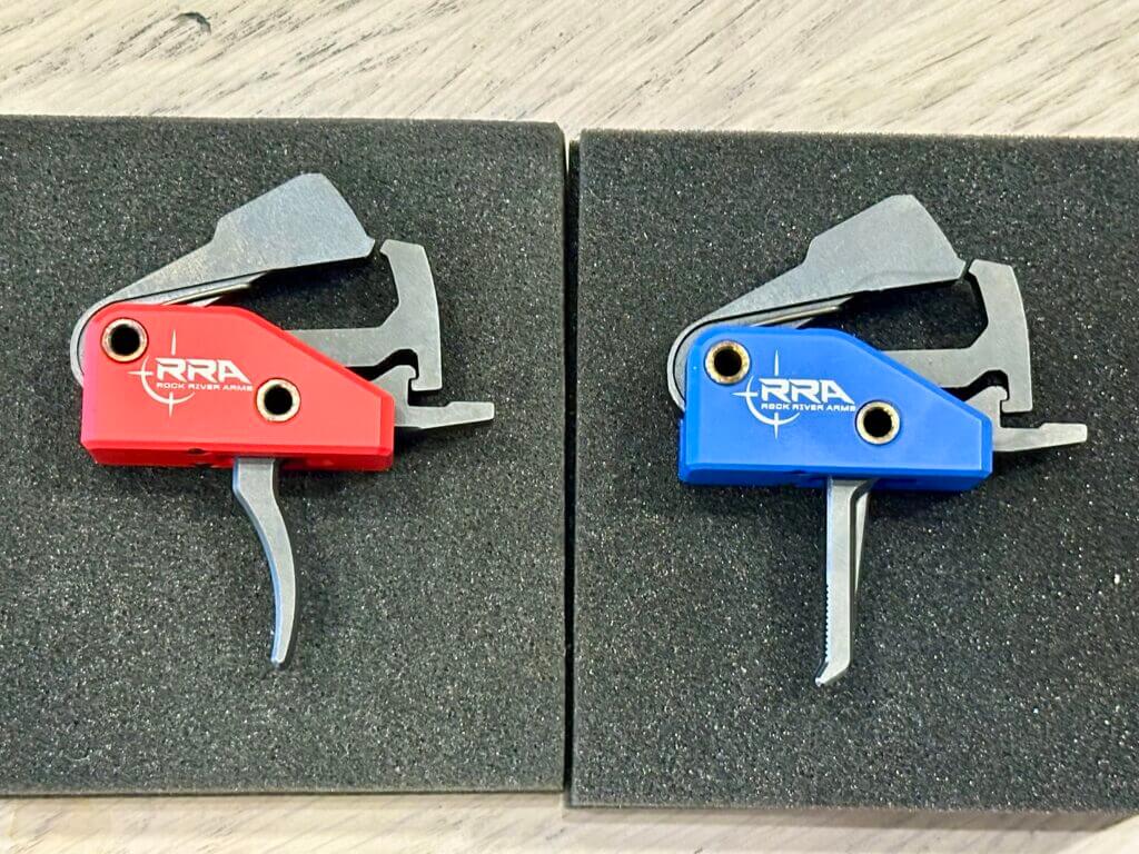 Rock River Arms drop in triggers displayed side-by-side. The red Duty Trigger is on the left and the Blue Precision trigger is on the right.