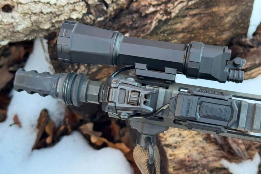 Holosun RAID mounted to rifle in front of snow-covered logs