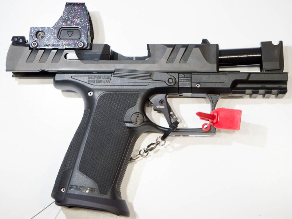 The gun laying on a white table , facing right, with the slide locked open.