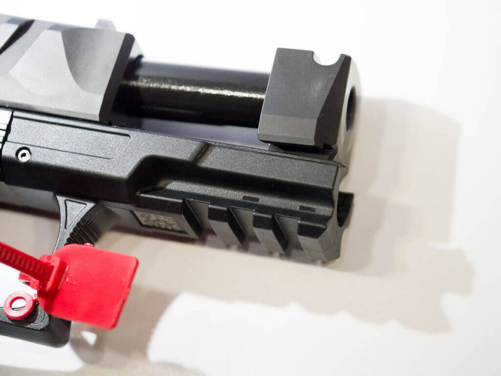 Close up of the fron of the gun, facing right, with the slide open showing the ported barrel device and pic rail.